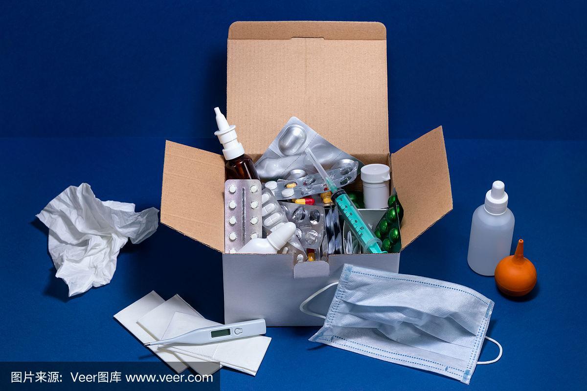 深藍色背景的紙板箱,里面有醫療用品.泡罩包裝的藥片.感冒和流感季節